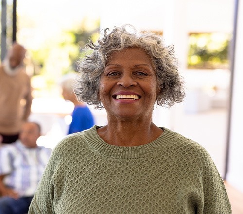 Woman in green sweater smiling with friends blurry in the background