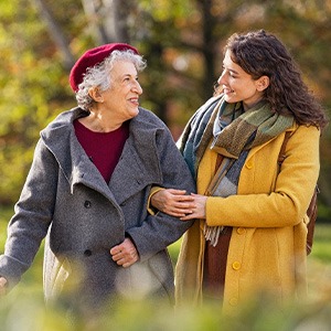 Older woman in gray coat speaking with younger woman in yellow jacket outisde