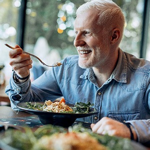 Man in denim shirt with white hair eating healthy meal