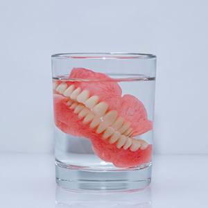 Dentures soaking in glass of liquid