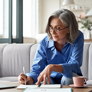 Woman in blue-collared shirt sitting at coffee table working