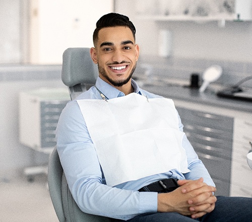 Man sitting in dental chair with hands folded