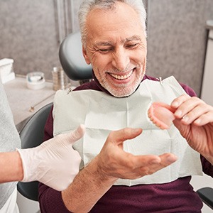 Male patient holding a denture at the dentist’s office