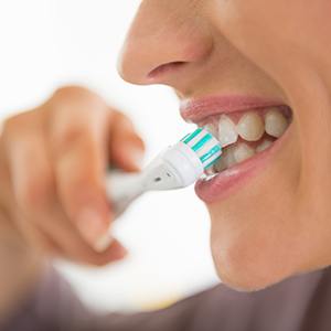 Nose-to-chin profile view of a woman brushing her teeth with an electric toothbrush