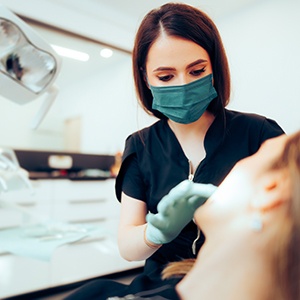 Dentist in green mask examining patient’s teeth