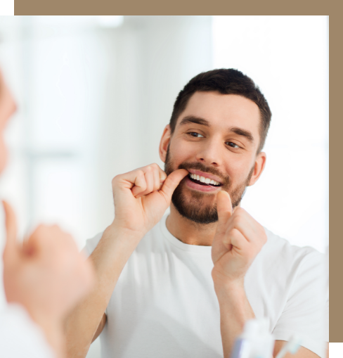 Man flossing his teeth in front of a mirror